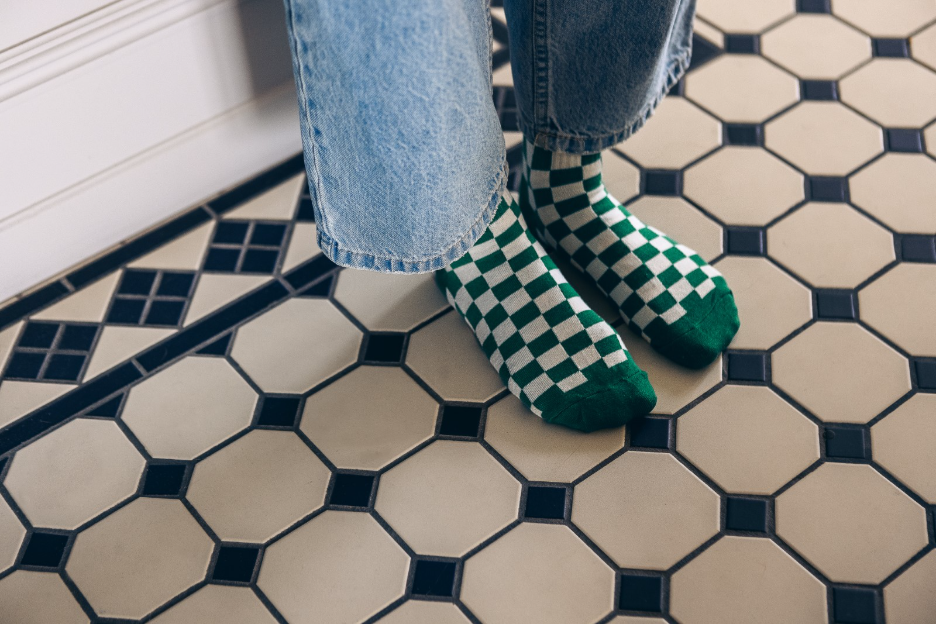 Neo Deco tile flooring with a bold geometric pattern, featuring cream octagonal tiles, dark accents, and a person wearing green checkered socks